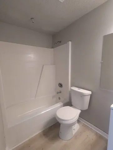 a white toilet sitting next to a bath tub