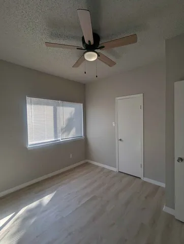 an empty room with a window and a ceiling fan