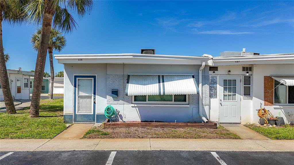 250 Rosery Road Northwest, Unit 228 Largo, FL 33770 - Photo 1 of 27 a view of a house with potted plants and palm trees