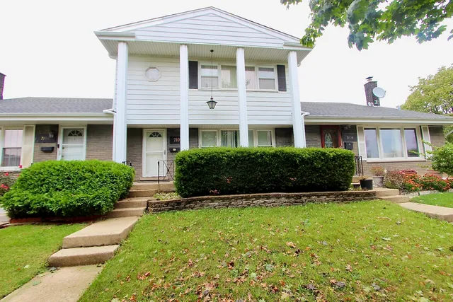 a front view of a house with a yard and plants