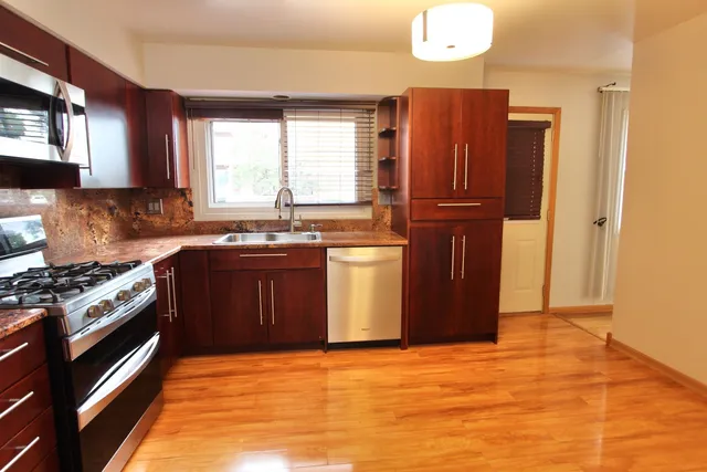 a kitchen with stainless steel appliances granite countertop a stove a sink and a refrigerator