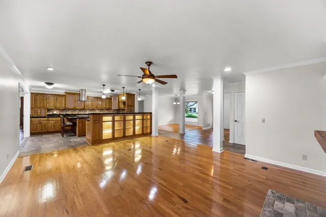 a view of kitchen and empty room with wooden floor