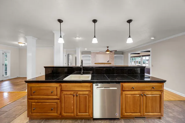 a kitchen with stainless steel appliances granite countertop wooden cabinets a sink a stove a dining table and chairs