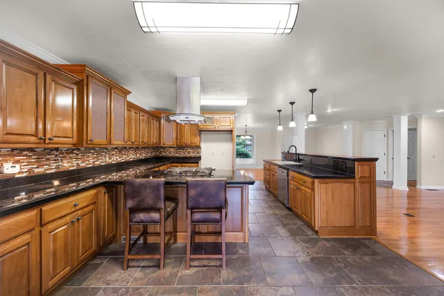 a kitchen with granite countertop stainless steel appliances a stove sink and cabinets