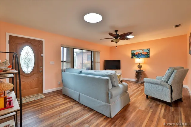 a living room with furniture a clock potted plant and a large window