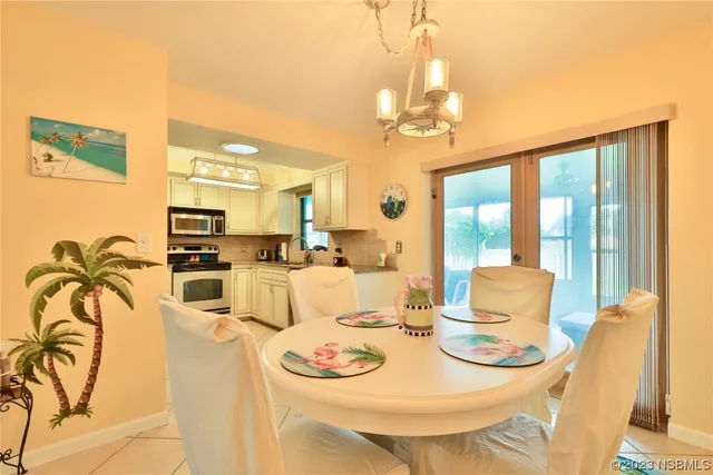 a dining room with furniture a chandelier and kitchen view