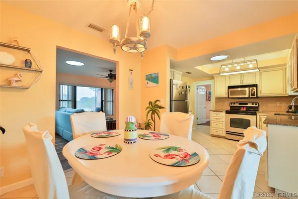 a dining room with stainless steel appliances a table and chairs with kitchen view