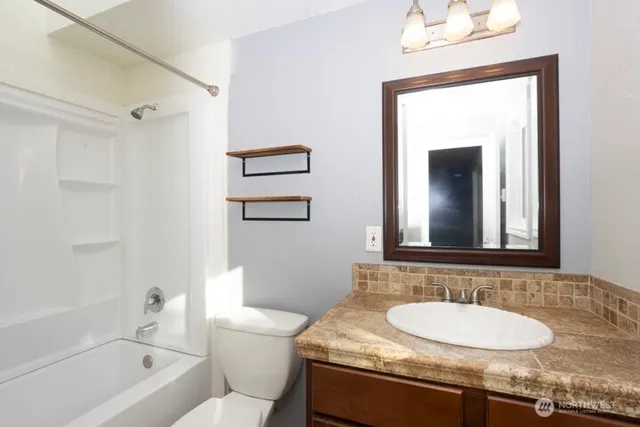 a bathroom with a granite countertop sink a toilet and shower