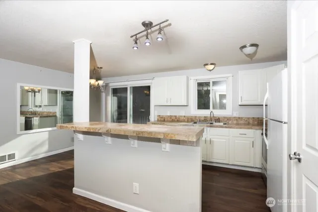 a large kitchen with kitchen island a stove a sink dishwasher a oven with wooden cabinets and floor