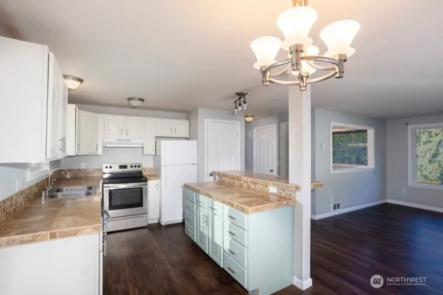 a kitchen with stainless steel appliances granite countertop a sink a stove and refrigerator