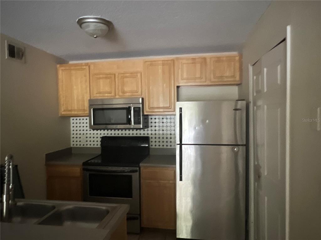 8939 Latrec Avenue, Unit 1205 Orlando, FL 32819 - Photo 12 of 15 a kitchen with a refrigerator and a stove top oven