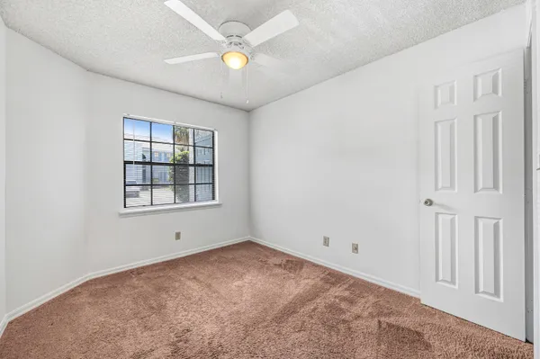 an empty room with windows and fan