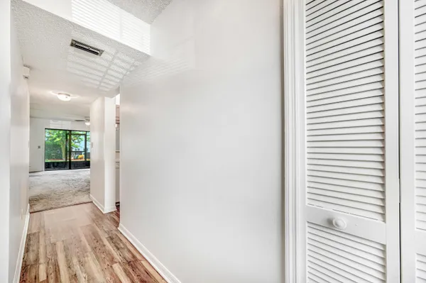 a view of a hallway with wooden floor and a bathroom
