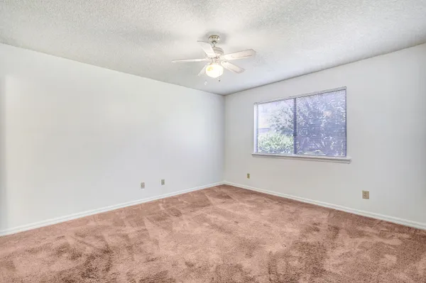 an empty room with a window and a fan