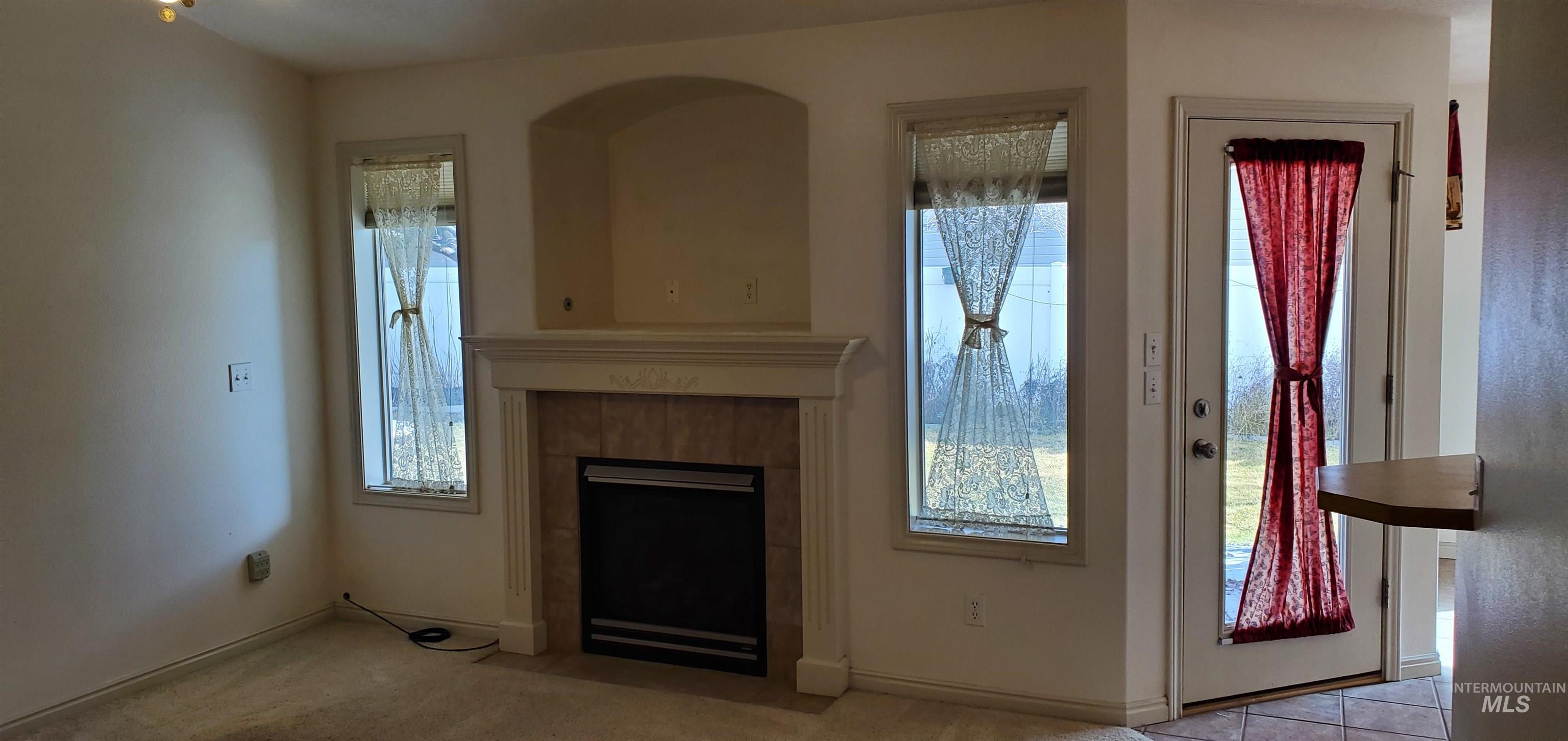 1000 North Rodeo Street Parma, ID 83660 - Photo 9 of 35 Unfurnished living room with a tiled fireplace, healthy amount of natural light, and carpet flooring