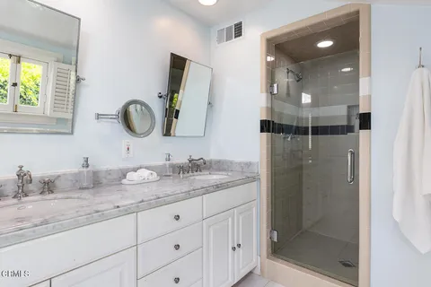a bathroom with a granite countertop sink a mirror and shower