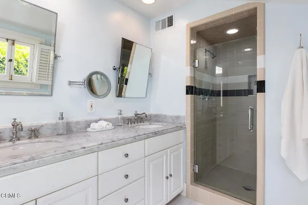 a bathroom with a granite countertop sink a mirror and shower