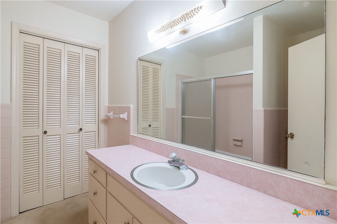 832 East Court Street Seguin, TX 78155 - Photo 18 of 31 a bathroom with a granite countertop sink a mirror and a shower