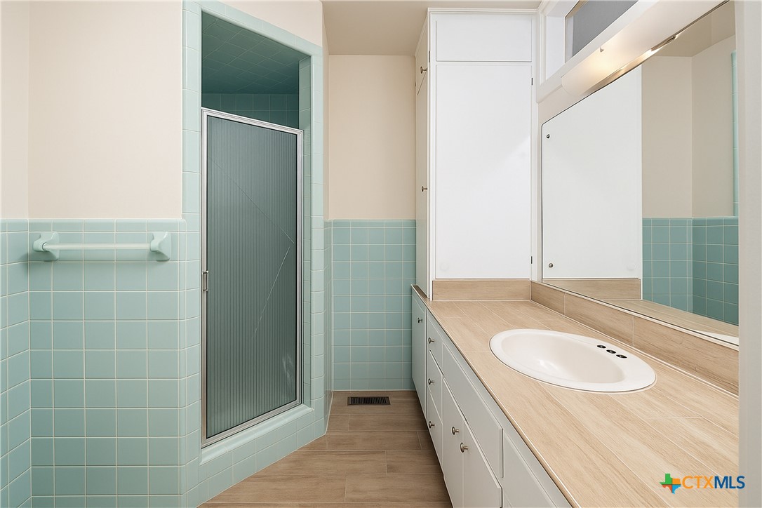 832 East Court Street Seguin, TX 78155 - Photo 23 of 31 a bathroom with a granite countertop sink a mirror and a bathtub