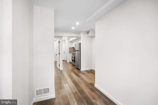 a view of a hallway with wooden floor and a bathroom
