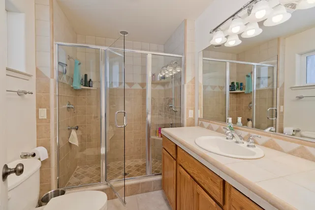 a bathroom with a shower sink vanity mirror and toilet