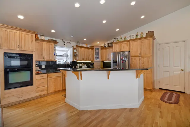 a view of kitchen with stainless steel appliances granite countertop a refrigerator a stove top oven and a sink