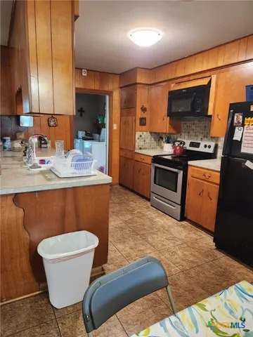 a kitchen with stainless steel appliances granite countertop a sink a stove a microwave a dining table and chairs