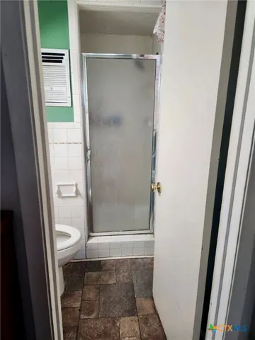 a bathroom with a toilet and a glass door shower