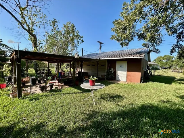 a view of a chair and tables in the garden in front of a house