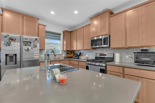 a kitchen with stainless steel appliances granite countertop a stove top oven a sink a refrigerator white cabinets and wooden floor