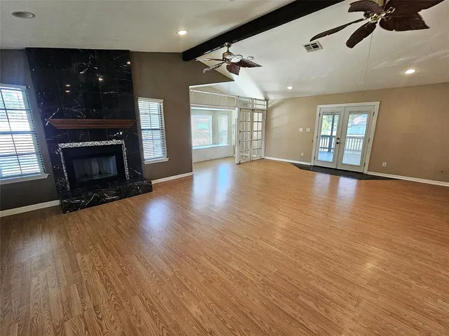 an empty room with wooden floor fireplace and windows