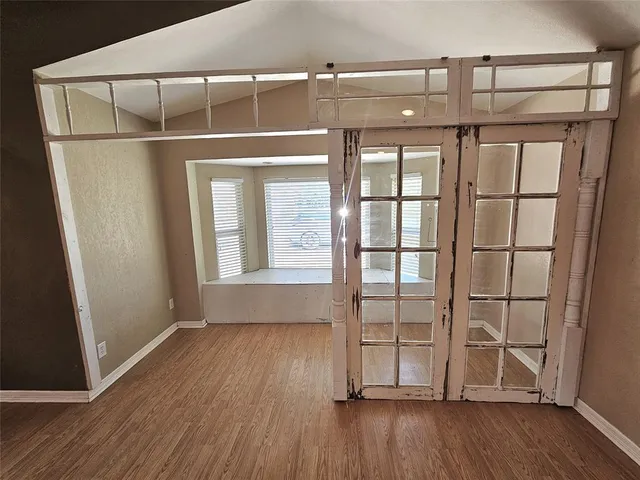 an empty room with wooden floor and windows