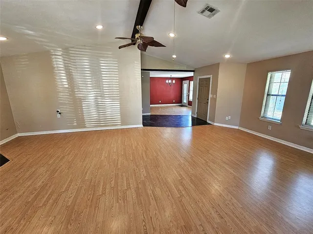 an empty room with wooden floor and windows