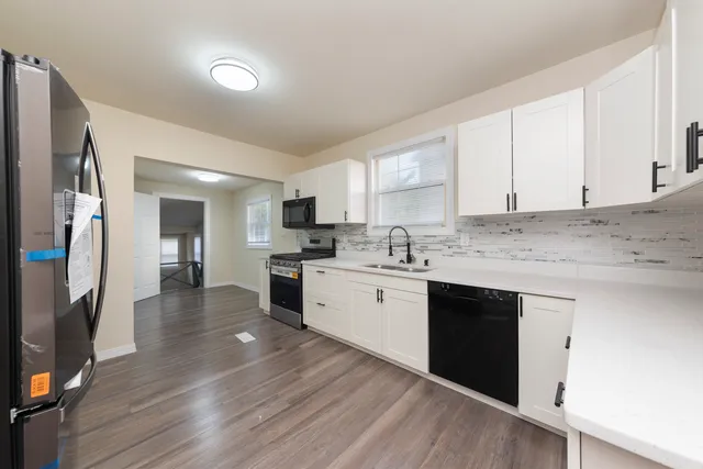 a kitchen with granite countertop white cabinets and stainless steel appliances