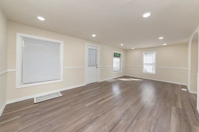 a view of empty room with wooden floor and window