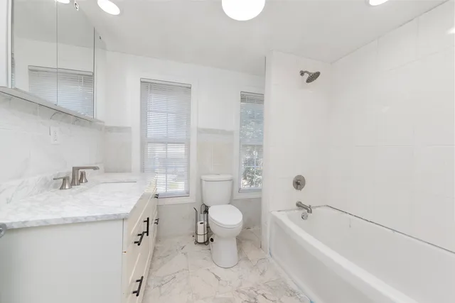 a bathroom with a granite countertop sink a toilet and bathtub