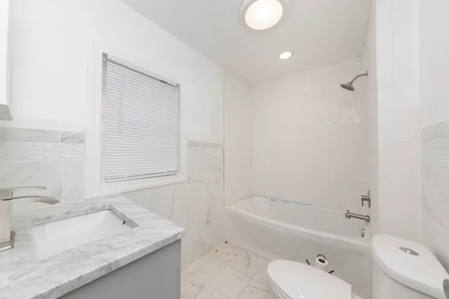 a bathroom with a granite countertop sink mirror toilet and bathtub