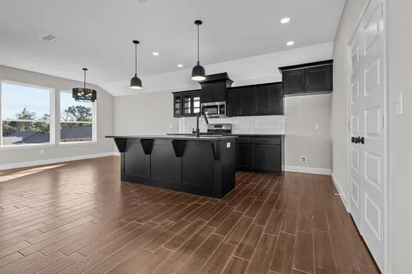 a kitchen with stainless steel appliances granite countertop a sink a stove and a wooden floors