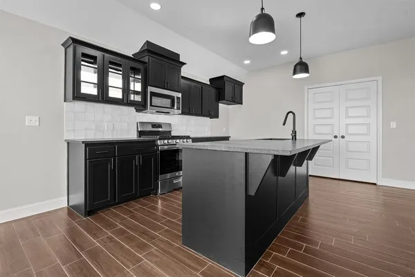 a kitchen with stainless steel appliances granite countertop a sink a stove and a refrigerator