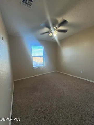 an empty room with windows and fan