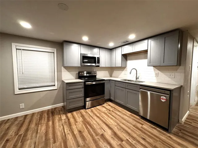 a kitchen with kitchen island granite countertop a stove top oven a sink dishwasher a dining table and chairs with wooden floor