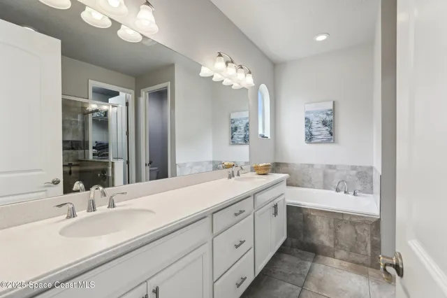 a spacious bathroom with a double vanity sink mirror and bathtub