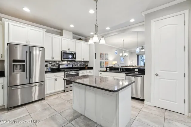 a kitchen with stainless steel appliances granite countertop a refrigerator a sink and white cabinets
