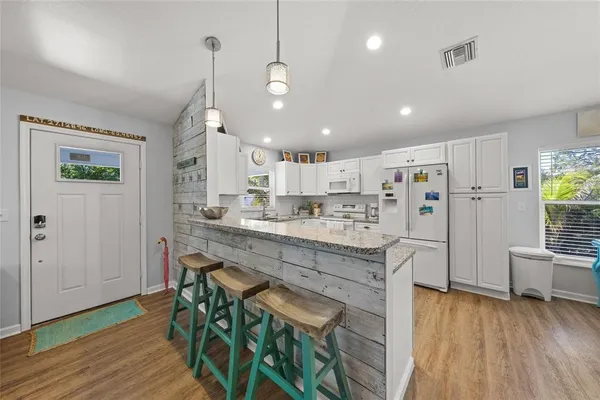 a kitchen with stainless steel appliances granite countertop a stove refrigerator a dining table and chairs with wooden floor