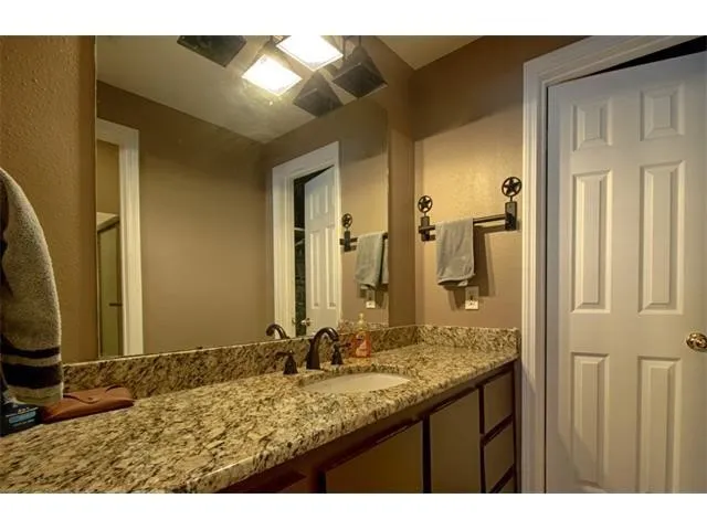 a bathroom with a granite countertop sink and a mirror