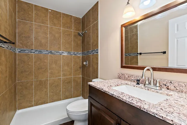a bathroom with a granite countertop sink a toilet and a mirror