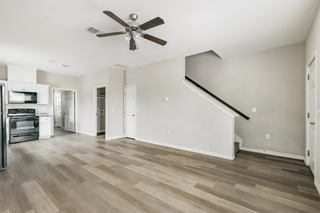 a view of a livingroom with a ceiling fan and staircase