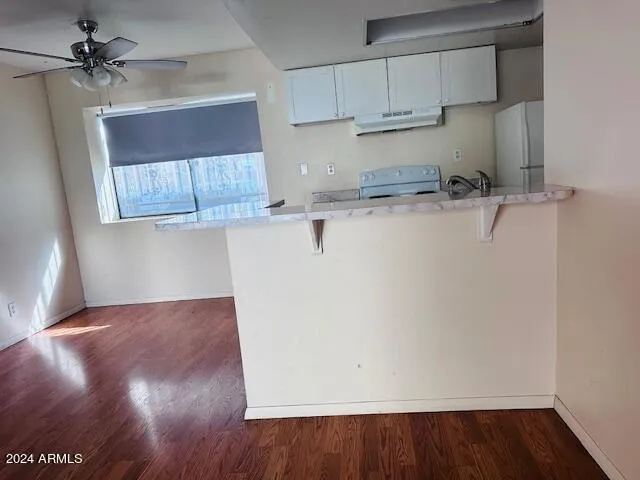 a view of kitchen with granite countertop white cabinets and wooden floor