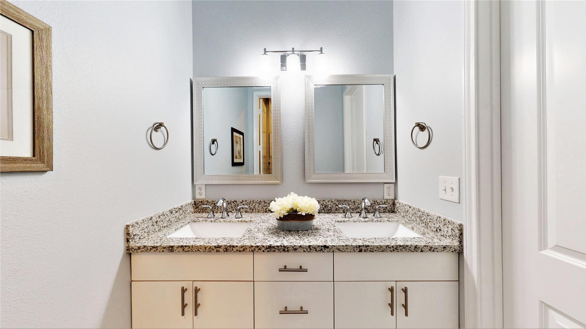 4924 Paradigm Ln Spring Spring, TX 77379 - Photo 13 of 18 This bathroom features a modern double vanity with granite countertops, dual mirrors, and sleek fixtures. The light, neutral color palette and elegant lighting create a bright and welcoming space.