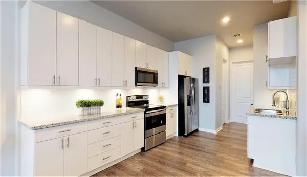 a kitchen with granite countertop white cabinets and stainless steel appliances